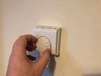 Image of hand adjusting a thermostat