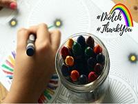 Image of a hand holding a crayon and a jar of crayons Image of a hand holding a crayon and a jar of crayons