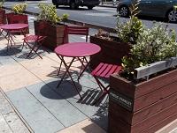 Image of table, chairs and planters on a pavement