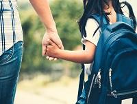 Image of girl with backpack holding her mother's hand and going to school