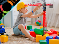 Image of a boy wearing a hard helmet sitting down playing with a crane and blocks