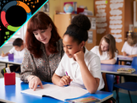 Image of teacher and pupil at a desk with other pupils in the classroom