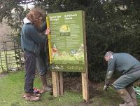 Image of two men putting up an information board in a churchyard