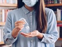 Image of someone in a facemask and sanitising their hands