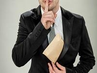 A man putting a finger to his lips as he steals money