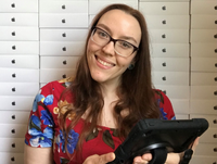 Image of Tilly Boscott, Digital Senior Library Assistant, using an iPad in front of a wall of iPads