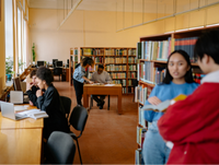 Image of six people working and chatting in pairs in a library setting