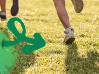 Image of children's feet running away across grass with a green arrow on the left hand side