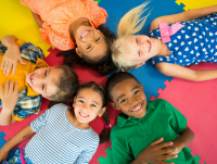 A group of children lying on the bed looking up at the camera