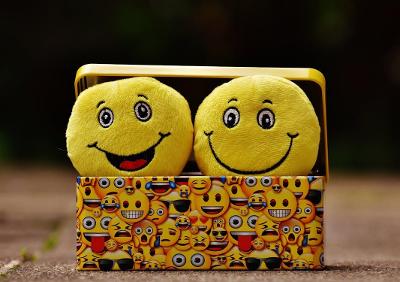 Two happy emoji cushions in an open tin