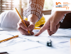 Image of a two people with technical drawings and a hard hat in the background