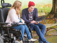 A person in a wheelchair talking to another person sitting next to them.