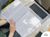 Image of a text book and a laptop