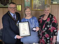 Image of Helen Kynaston receives her Silver Kite Award from the Chair of Powys County Council, Cllr William Powell, during a visit to Newtown Community Kitchen. Also pictured is Cllr Joy Jones, county councillor for Newtown East.