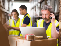 Man in high vis on a laptop in a factory