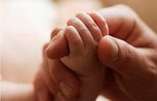 Image of a baby's hand holding an adults hand