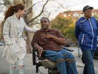 Image of a man in a wheelchair with 2 women walking beside him