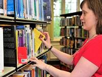 Image of librarian putting a book on the shelf